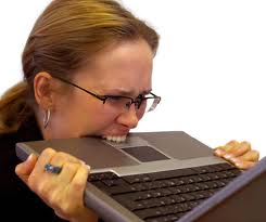 Woman biting her laptop in frustration